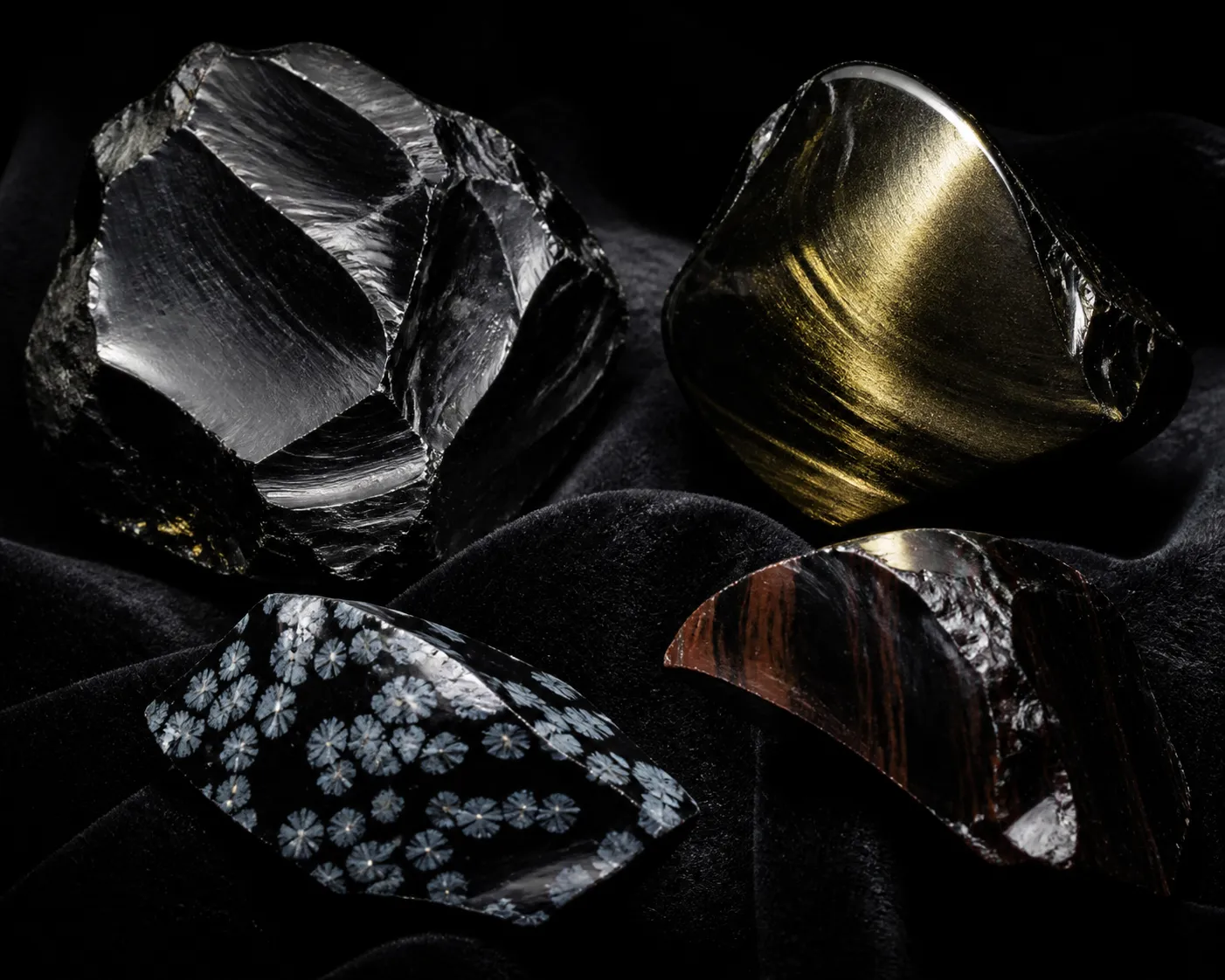 Close view of obsidian specimens showing glassy fracture edges, sheen, and varied surface textures